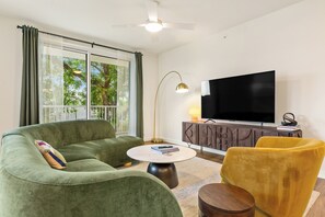 A living room with a sofa, a yellow chair, a round coffee table, a TV, and a cabinet. - South Lamar Stay w/ Private Balcony | Pool, Terrace, On-Site Dining | The Code (Austin)