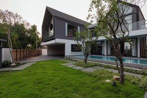 Una casa moderna con piscina, césped cuidado y valla de madera.