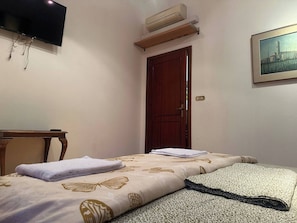 A bedroom with a bed, a TV, an air conditioner, a wooden door, and a painting on the wall. - Room-b&b di Jerome Camera 1 (Bologna)