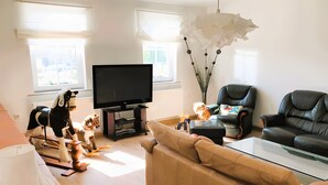 Una sala de estar con un sofá, televisor, una silla y una lámpara.
