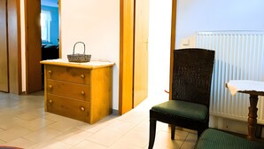 Una habitación con cómoda de madera, una silla de mimbre y un radiador.