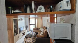 Un espacio habitable compacto con kitchenette, un sofá y una televisión.