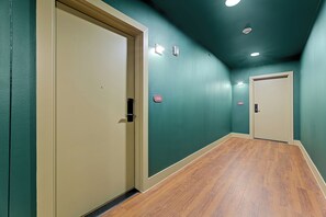 Un couloir aux murs de couleur turquoise, doté d’un plancher en bois et de deux portes.