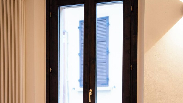 Una stanza con una finestra, un termosifone e un letto con copriletto blu e bianco.