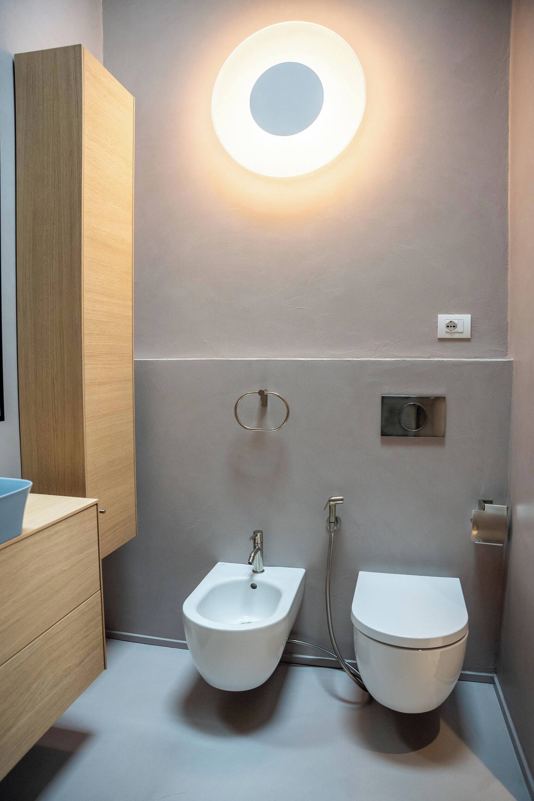A modern bathroom with a bidet, toilet, and a wooden vanity.