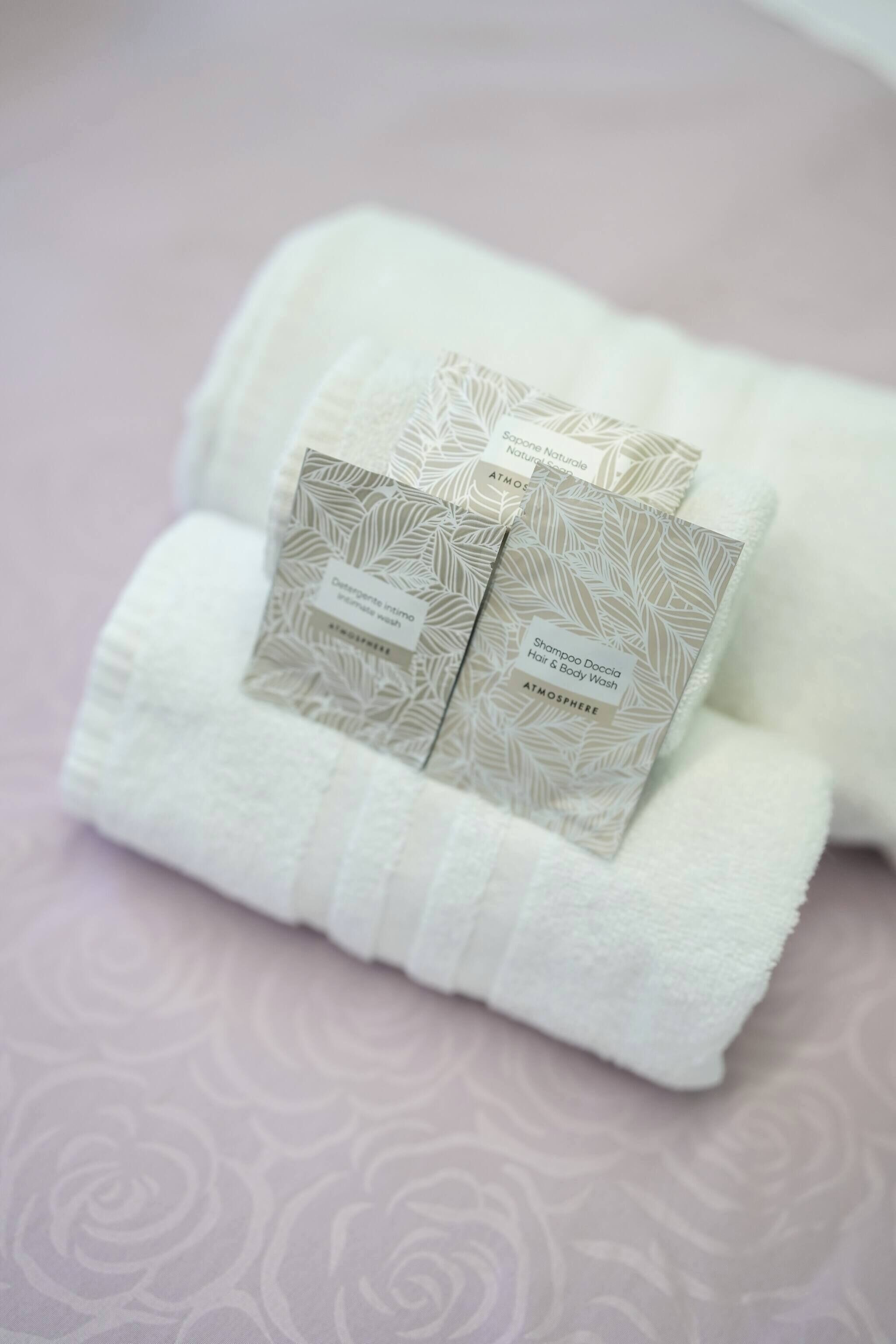 A neatly folded white towel with two packaged hair and body wash products on top.
