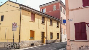 Uma rua estreita com edifícios em ambos os lados, uma bicicleta estacionada na calçada e uma placa de proibido estacionar.