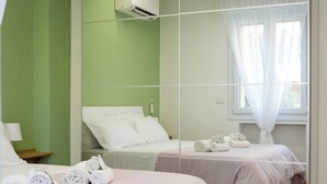 Um quarto moderno com duas camas, um espelho grande e uma janela com cortinas leves.