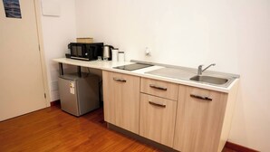 Una cocina compacta equipada con microondas, cafetera y un refrigerador pequeño.