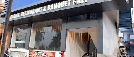 A building with a sign for 'Rooms & Banquet Hall' and a staircase leading to the entrance.