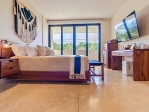 A bedroom with a bed, a desk, a television, and a large window. - Modern 2BR Apartment in Tulum  Great Location (Tulum)