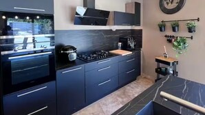 Una cocina moderna con armarios oscuros, una estufa a gas y un horno empotrado.