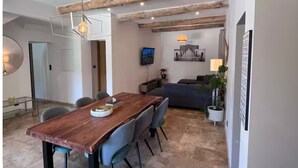 Un comedor con una mesa y sillas de madera, un sofá y un televisor montado en la pared.