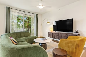 A living room with a sofa, a yellow chair, a round coffee table, a TV, and a cabinet. - Private Balcony | Resort Pool, Terrace w/ Views, On-Site Dining | The Code (Austin)