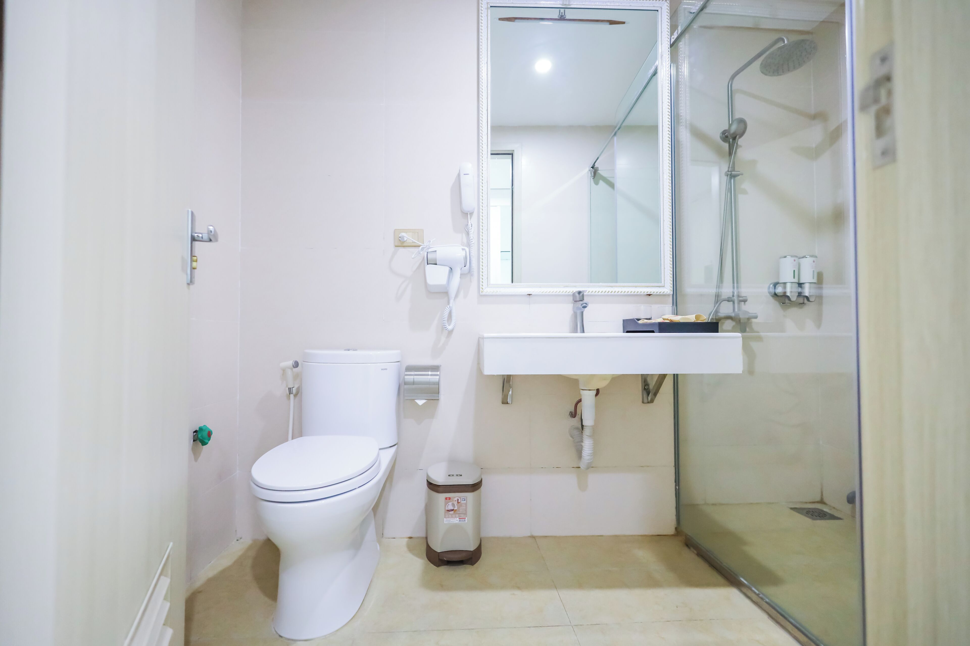 A bathroom with a toilet, a sink, a mirror, and a shower enclosure.