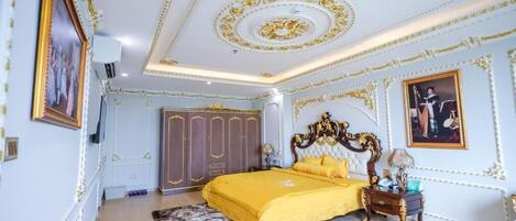 Un dormitorio lujoso con una cama grande, techo decorado y muebles clásicos.
