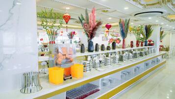 A well-lit, modern interior with a marble floor, a long counter with various items, and decorative plants.