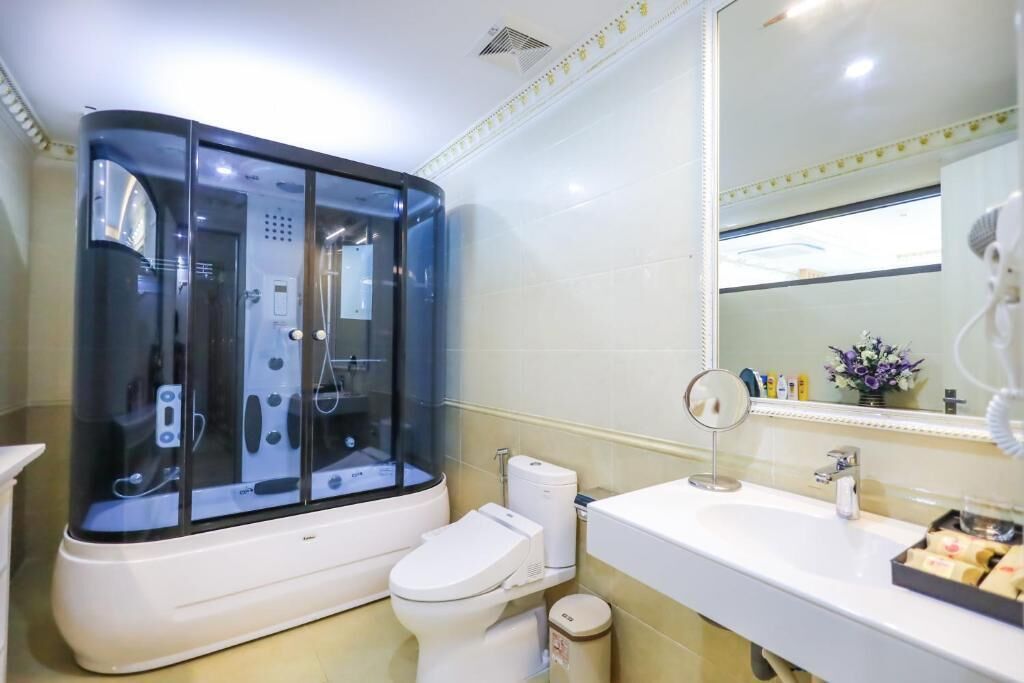 A modern bathroom with a glass-enclosed shower, a white toilet, and a sink with a mirror.