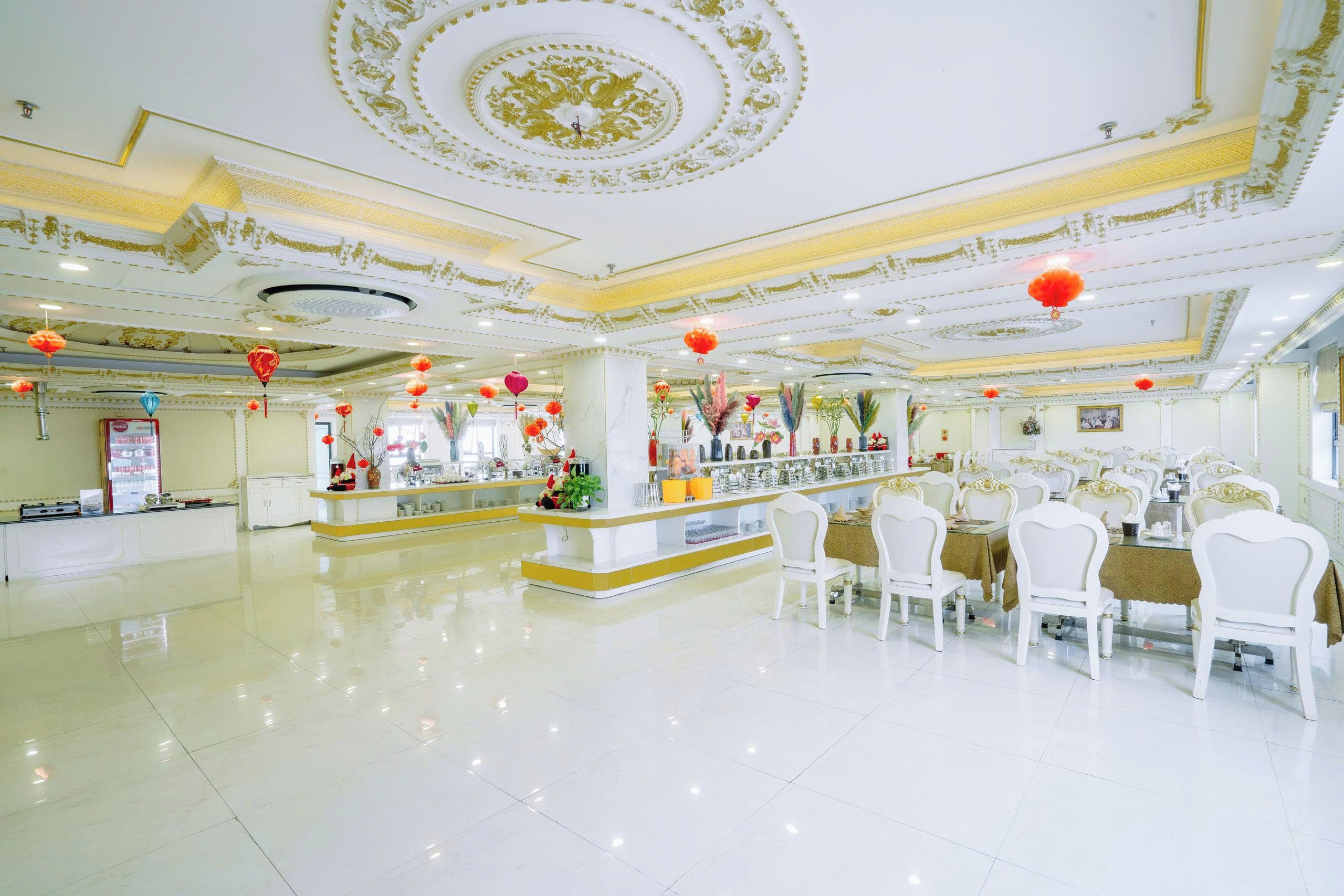 A spacious hotel lobby with a central bar area, white furniture, and decorative ceiling details.