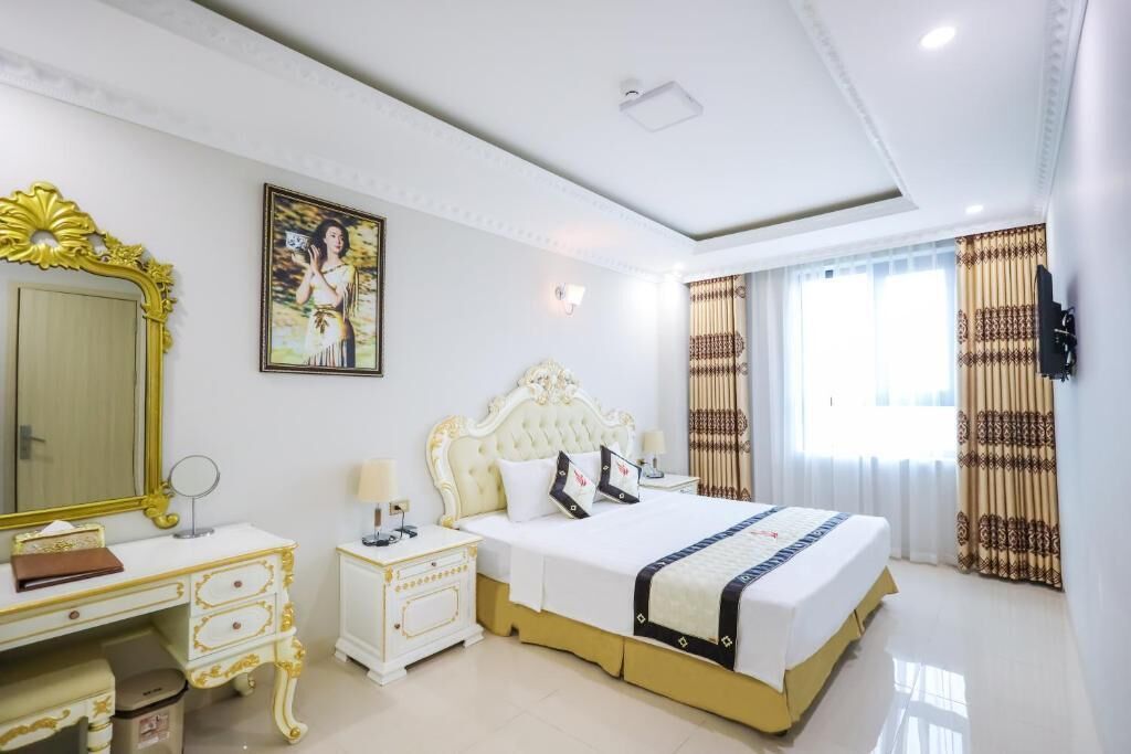 A hotel room with a large bed, a vanity with a mirror, and a television on the wall.