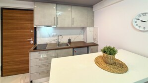 Eine moderne Küche mit weißer Arbeitsplatte, Spüle aus Edelstahl und grauen Schränken.