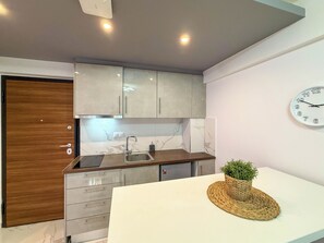 A modern kitchen with a white countertop, stainless steel sink, and grey cabinets. - Welcome to ILEKTRA Suite no.4 By SDR (Paralia)