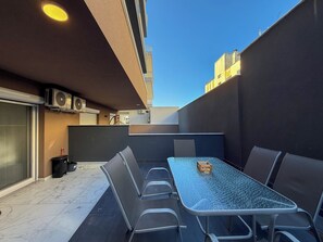 An outdoor patio with a table and chairs, air conditioning units, and a view of buildings in the background. - Welcome to ILEKTRA Suite no.4 By SDR (Paralia)