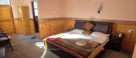 A bedroom with a large bed, wooden headboard, a nightstand, and a window.
