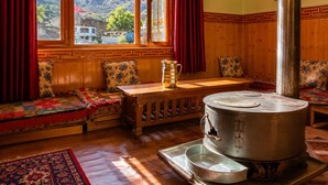 A cozy room with a large window, wooden bench, and a traditional stove. - Tanghaa Resort By Mountain Bee (Nako)