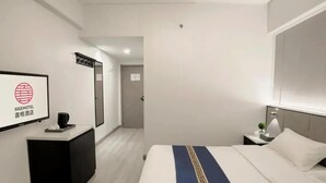 Een hotelkamer met een bed, nachtkastje, bureau, spiegel en een bord aan de muur.