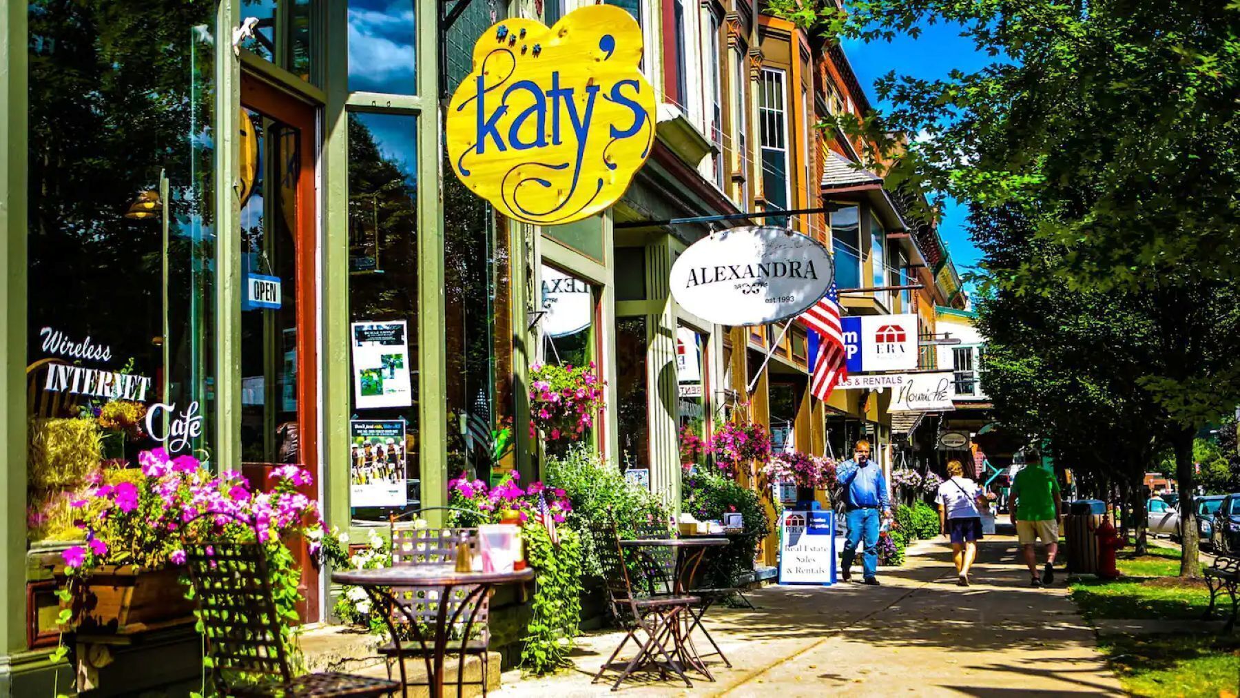 A street view with a cafe named 'Katy's' and a real estate sign for 'Alexandra'.