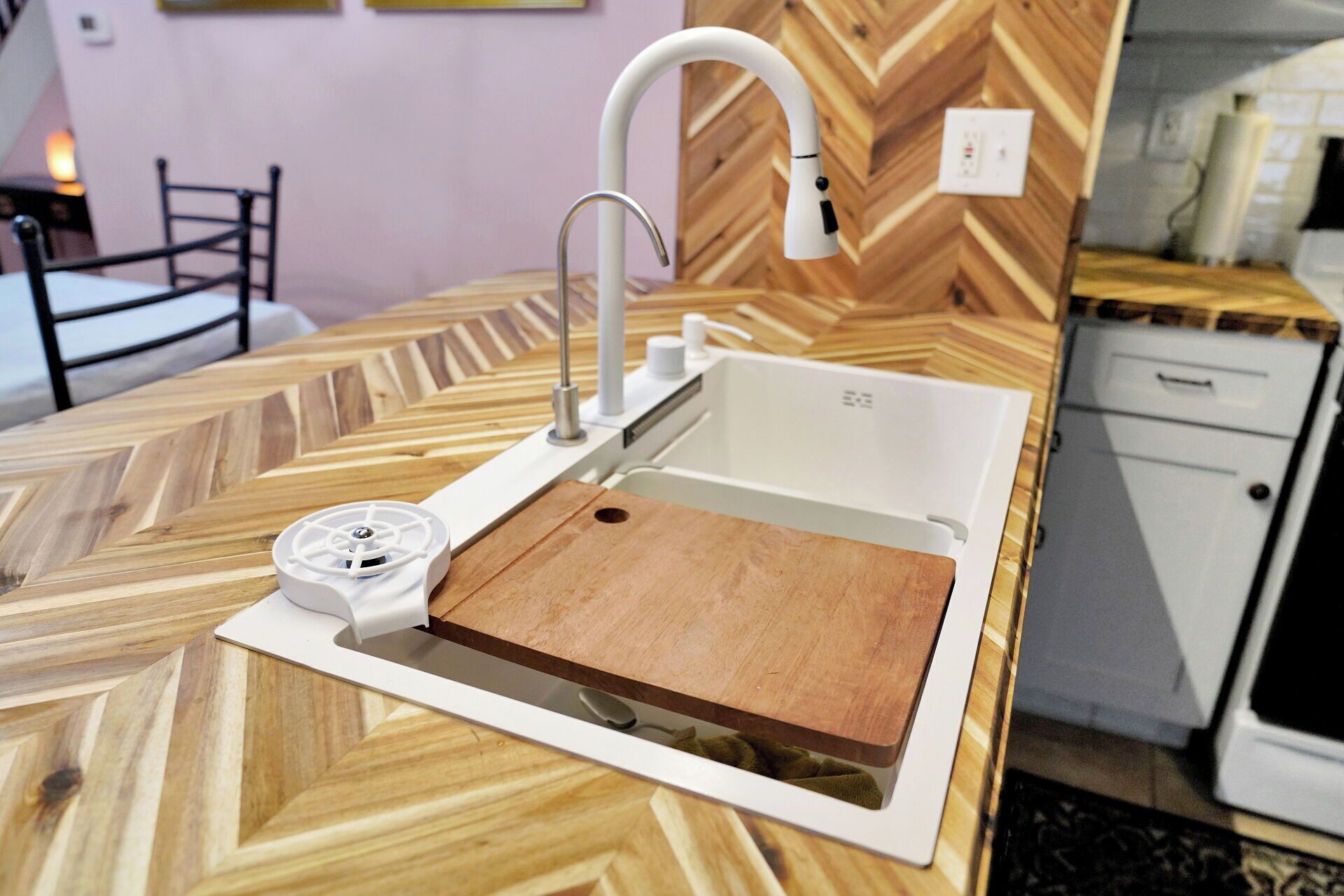 A kitchen with a modern sink, a wooden countertop, and a herringbone-patterned backsplash.