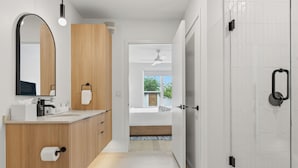 A modern bathroom with a wooden vanity, a large mirror, and a glass shower enclosure. - Private Balcony | Resort-Style Amenities | Pool, Dining, Terrace, Views (Austin)