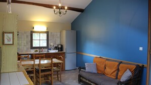 A compact kitchen with a dining area, a sofa, and a chandelier. - Le vieux four self-catering cottage in the countryside (Corbarieu)