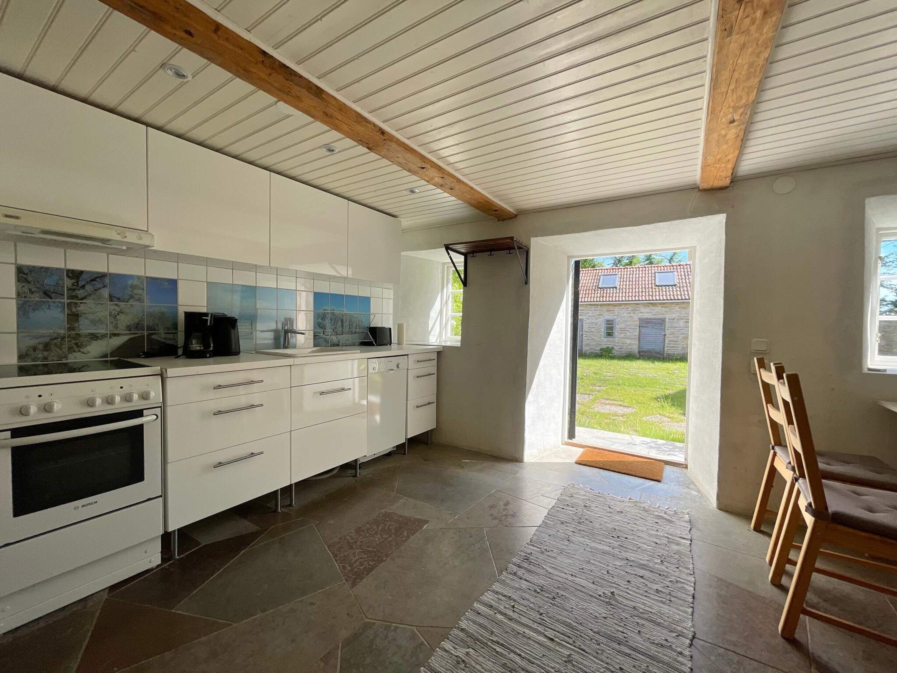 A modern kitchen with white cabinets, a Bosch oven, and a tiled backsplash.