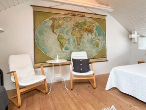 Una habitació amb dues cadires, una taula petita i un mapa mundial gran penjat a la paret.