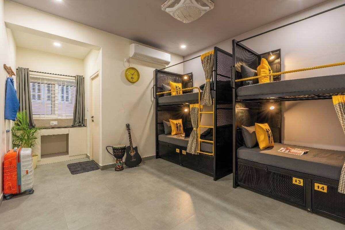 A compact room with bunk beds, a desk, a guitar, and a suitcase.