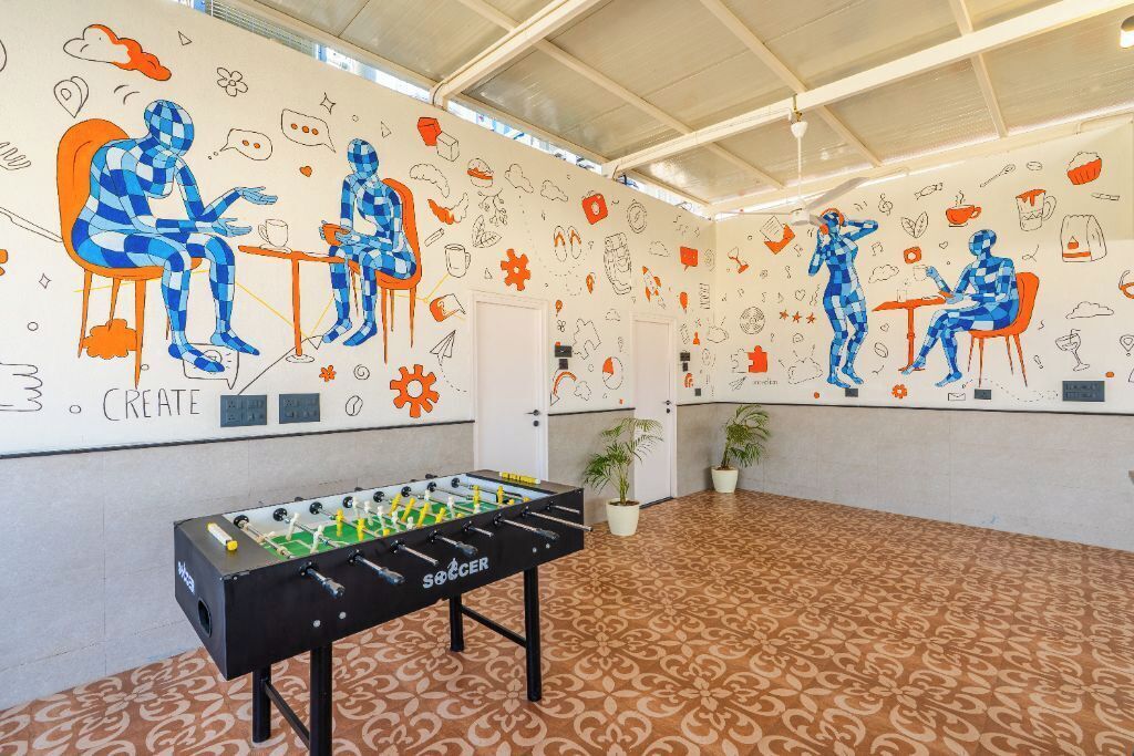 A room with a foosball table, patterned carpet, and walls decorated with various doodles and illustrations.
