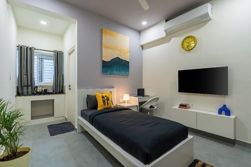 Et moderne hotelværelse med seng, skrivebord, fjernsyn og et billede på væggen.