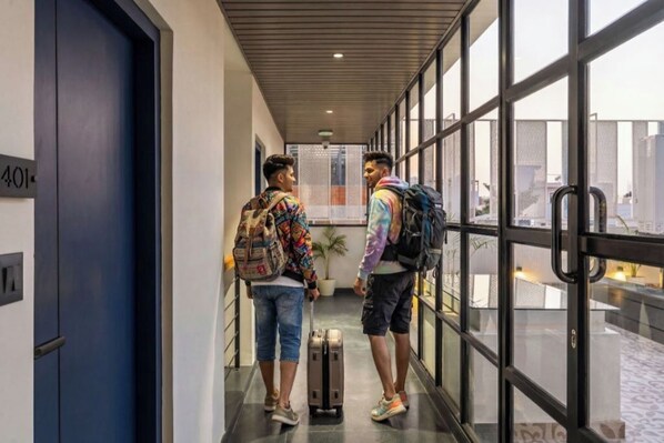 A hallway with a blue door marked "401" and a glass door leading to an outdoor area. - The Hosteller Bangalore, HSR Layout (Bengaluru)