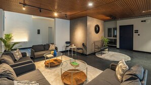 A modern interior with a wooden ceiling, grey sofas, a round coffee table, and a small side table. - The Hosteller Bangalore, HSR Layout (Bengaluru)