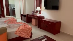 A hotel room with a bed, a sofa, a TV, a desk, and a wardrobe. - Oyster Bay Beach Suites Luxury Studio with a sea view (Sea Governorate)