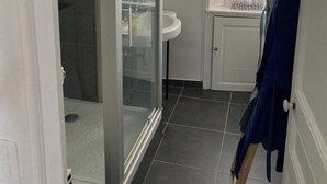 A bathroom with a glass shower enclosure, a sink, and a window with curtains. - House Nantes center in private cul-de-sac (Nantes)