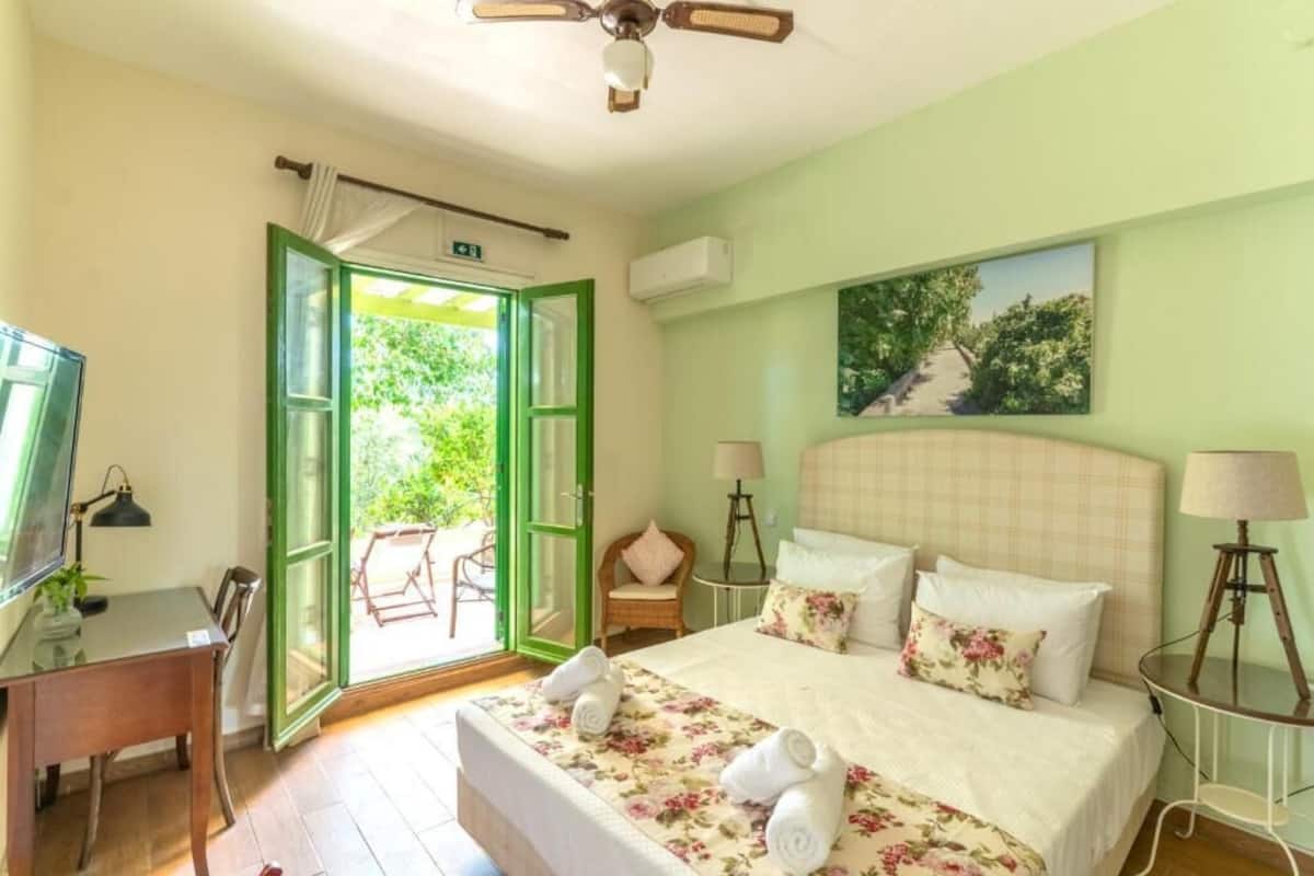 A hotel room with a bed, a desk, a chair, a TV, and a painting on the wall.