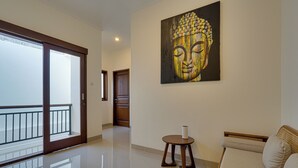 En rummelig opholdsstue med et stort Buddha-maleri, en sofa og et lille bord.