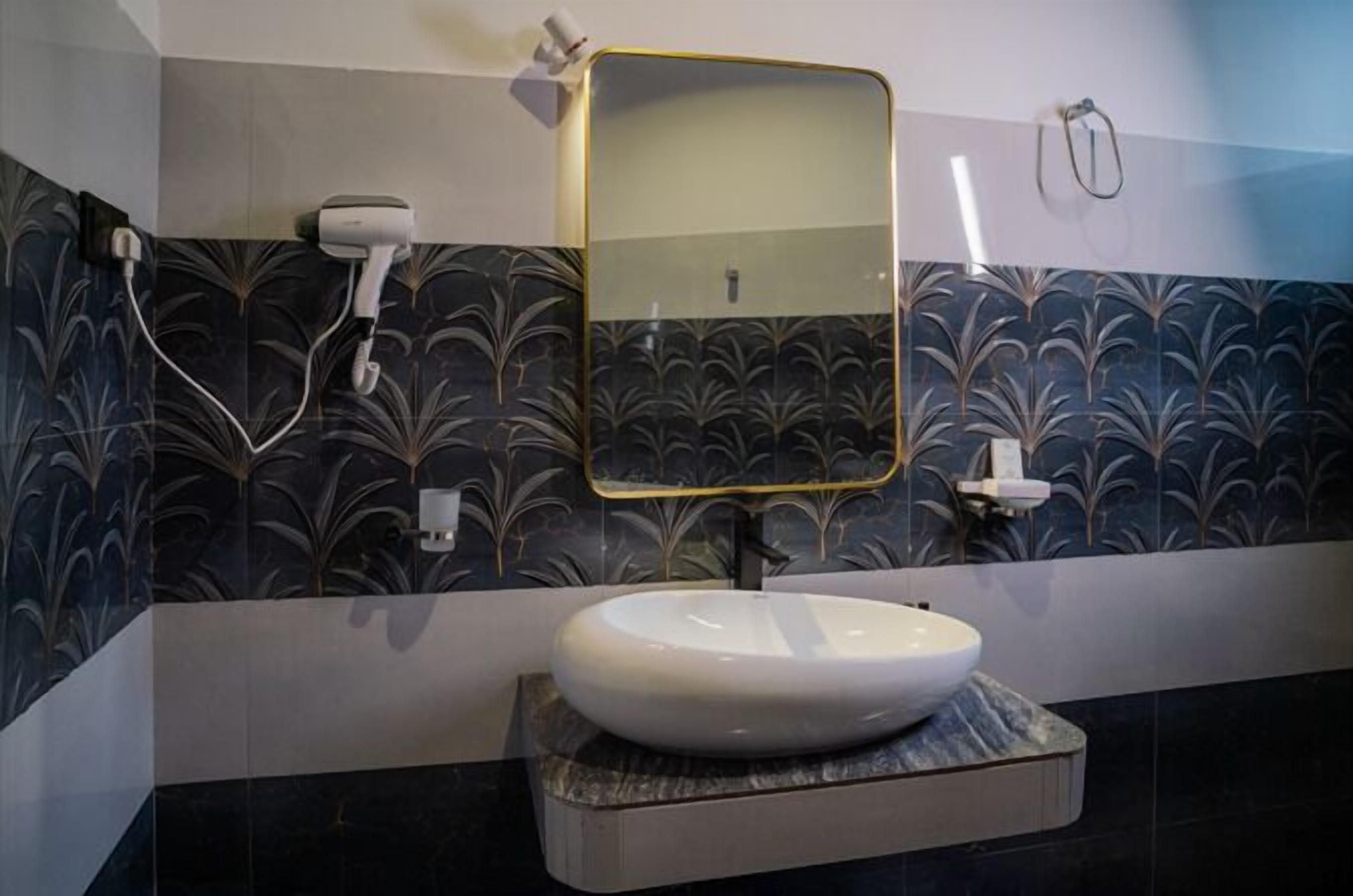 A bathroom with a white sink, a gold-framed mirror, and a towel rack.