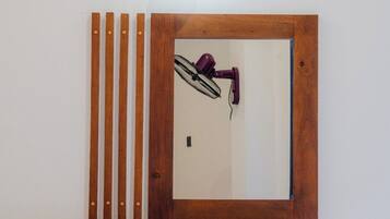 Una estantería de madera anclada a la pared, un abanico morado y una lámpara.