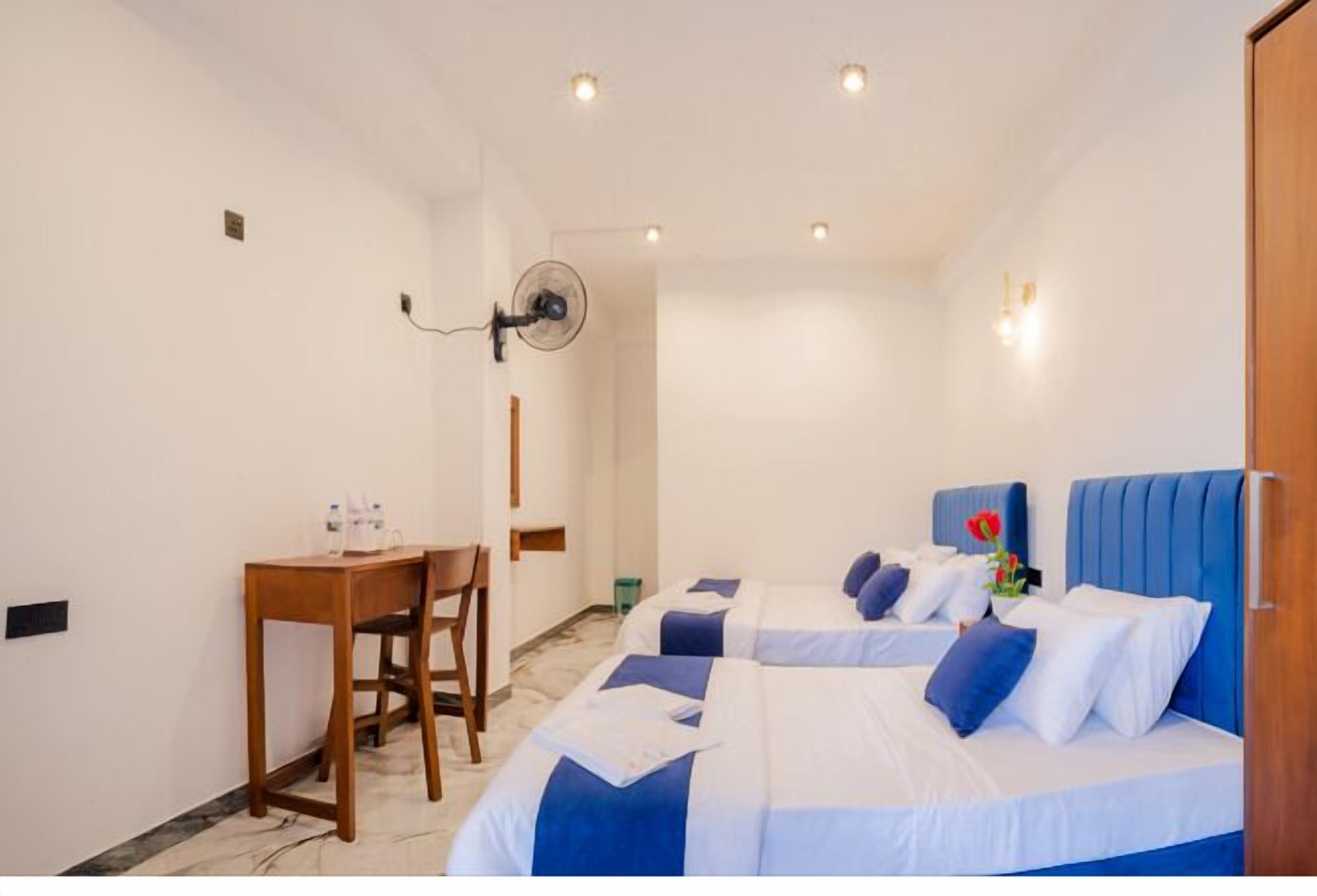A hotel room with two beds, a desk, and a chair.