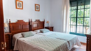 Una cama doble con edredón acolchado, dos mesitas de noche con lámparas y una ventana con vistas a zonas verdes.