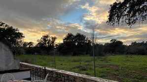 Un patio con un muro de piedra, una mesa de metal y sillas.